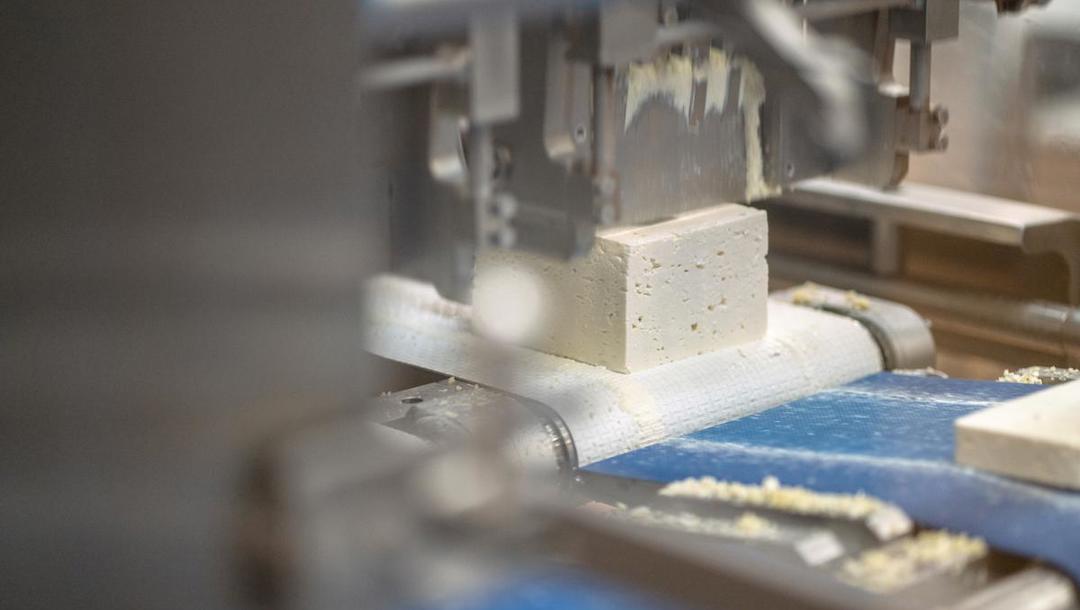 Efterfølgende skærer en maskine osten i skiver 