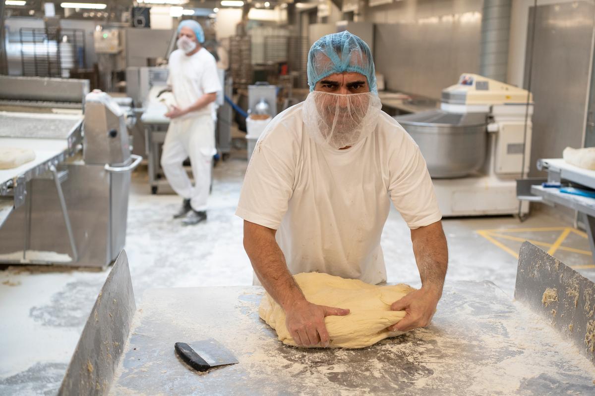 Mohammed Alasar lægger kræfterne i, når han ælter dejen til kanelsnurrer. Herefter klarer to maskiner at rulle dejen flad og sprøjte den med smørcreme med kanel. 