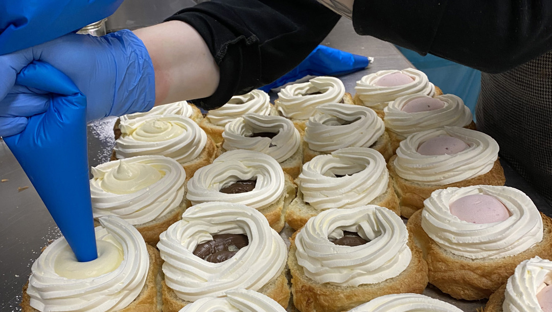 Når bollerne har fået toppingen på, sprøjtes creme og flødeskum i.