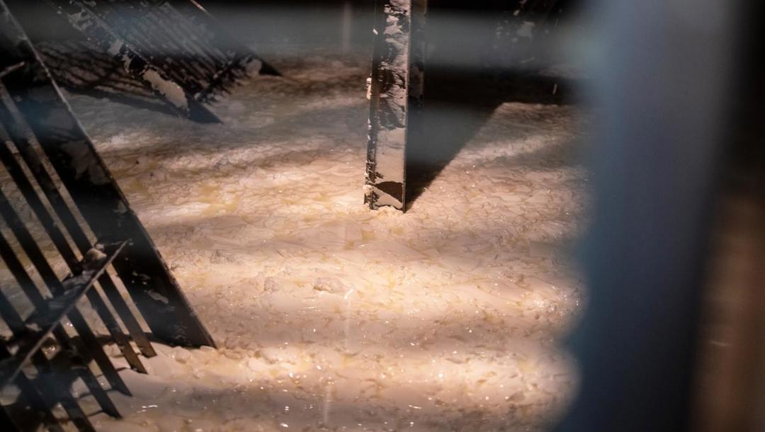 Osten skæres i stykker af røreværket. Der er skarpe knive på den ene side, og på den anden side er der runde kanter på stålet. 