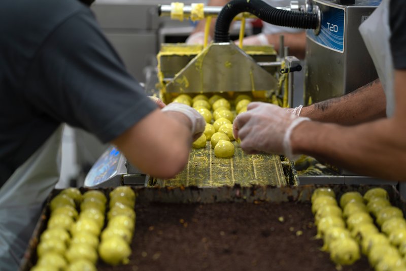 Baks Bakery and Deli kan producere 30.000 romkugler om dagen, hvis ordrebogen er tyk. Frivillige i organisationen Cykelnerven solgte 42.000 romkugler til gavn for forskningen i Sclerose hen over påsken sidste år. Dem lavede bageriet på to dage oveni deres normale produktion, som varierer fra dag til dag alt efter efterspørgsel. 